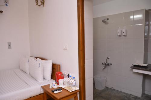 a room with a bed and a shower and a table at Cours CHABROL in Puducherry
