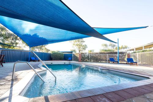 a blue umbrella over a swimming pool at Coral Coast Tourist Park in Carnarvon