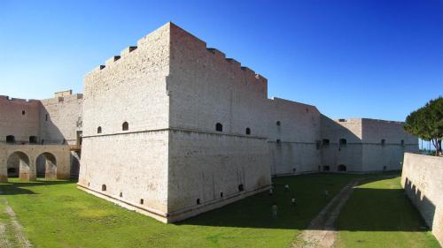 een groot bakstenen gebouw met een groen veld voor de deur bij Marco Polo B&B in Barletta