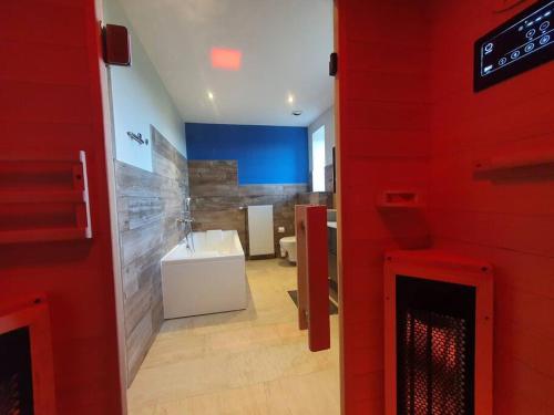 La salle de bains est pourvue d'un lavabo et d'un mur rouge. dans l'établissement Chez Arnaud sauna et jacuzzi, à Saint-Maurice-sur-Loire