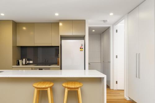 a kitchen with a white counter and two stools at Elegant and Cosy Haven in Lively Kingston Foreshore - Hosted by Canstay in Kingston