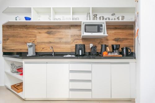 a kitchen with white cabinets and a microwave at Exclusivo Apê na Orla Bardot Vista para o Mar in Búzios