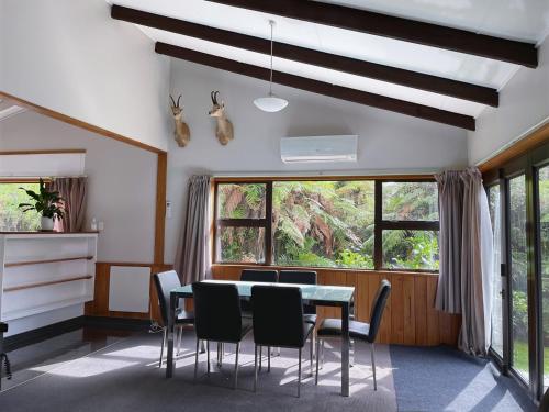a dining room with a table and chairs and windows at Central & Relaxing in Franz Josef