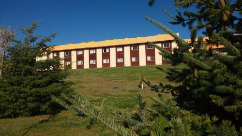 a large building with a field in front of a tree at Hotel Picos Del Sur in El Calafate
