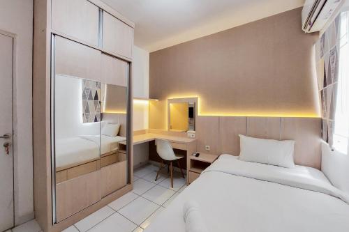 a hotel room with a bed and a desk at Cozy and Minimalist Studio (No Kitchen) at Aeropolis Apartment By Travelio in Tangerang