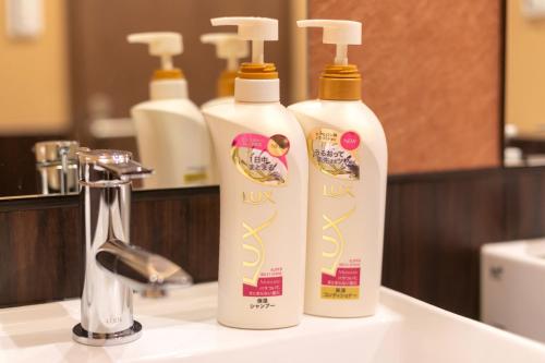 two bottles of lotion sitting on a bathroom sink at IKIDANE Cozy Hotel Haneda Airport - Vacation STAY 25840v in Tokyo