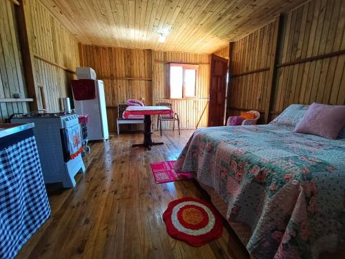 a bedroom with a bed and a refrigerator and a table at Recanto do Cachoeira do Nassuca in Cambará