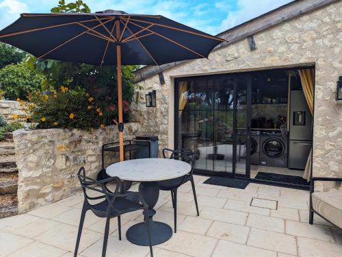 a table and chairs with an umbrella on a patio at Charmante Chambre d'Hôtes avec Piscine Chauffée et Terrasse Privative dans le Parc de la Brenne - FR-1-591-597 in Paulnay