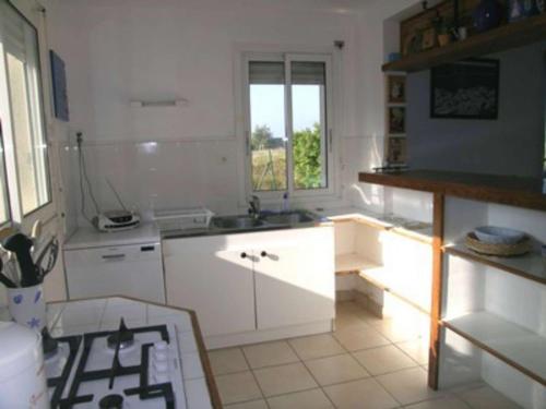 une cuisine avec des armoires blanches, un évier et une fenêtre dans l'établissement Maison familiale 4 pièces, animaux acceptés, près plage - FR-1-479-164, à Plouharnel