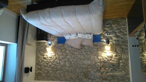 a bedroom with a bed and a stone wall with lights at Le Petit Chalande in Autrans