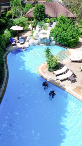 a large swimming pool with chairs and blue water at Palm Garden Resort in Rawai Beach