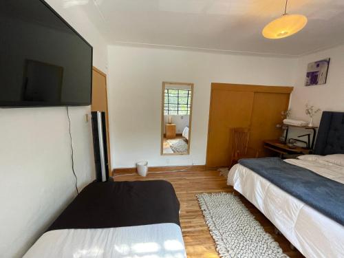 a bedroom with two beds and a flat screen tv at Hostal Roma Condesa in Mexico City