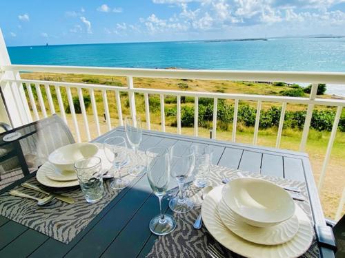 a table with plates and wine glasses on a balcony at Excellence Suites Orient Beach Oceanview King-Size Beach Pool Parking in Cul de Sac