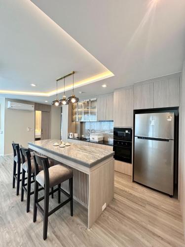 a kitchen with a large island with chairs and a refrigerator at The Regent Phuket Bangtao Beach in Bang Tao Beach