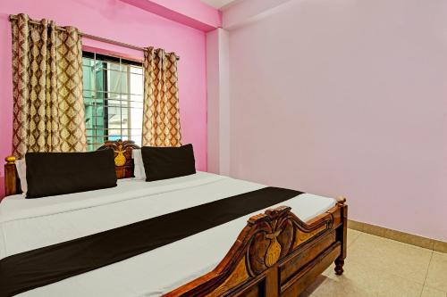 a bedroom with a large bed with pink walls at Hotel O Mahalaxmi lodge in Cuttack