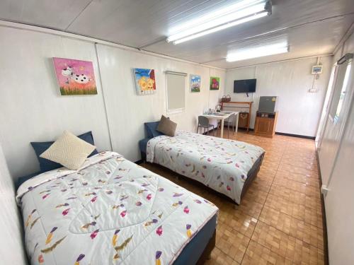 a bedroom with two beds and a desk in it at แอนฟาร์มรีสอร์ทแอนด์คาเฟ่ลำปาง in Mae Mo