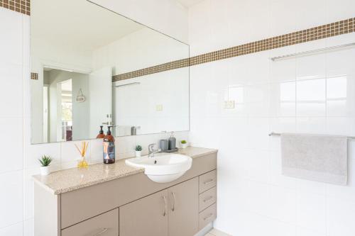 Un baño blanco con lavabo y espejo. en Swan Lake View House, en Berrara