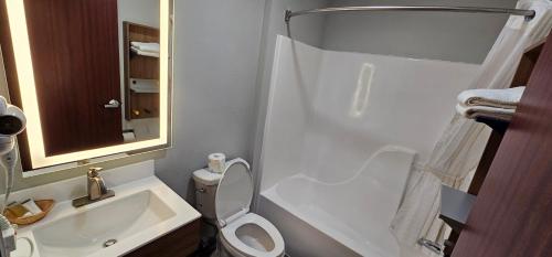 a bathroom with a toilet and a sink and a mirror at Microtel Inn & Suites by Wyndham Tulsa - Catoosa Route 66 in Tulsa