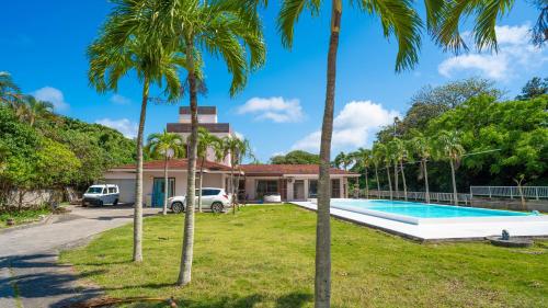 a house with a swimming pool and palm trees at SOLAIZ Ishigaki Island in Kabira