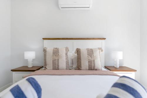 a bedroom with a white bed with two lamps at Belle Escapes Sea Bon in Trinity Beach
