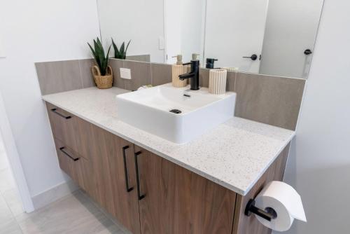 a bathroom with a white sink and a mirror at Belle Escapes Sea Bon in Trinity Beach