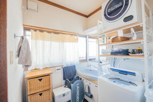 a small room with a sink and a washing machine at yururito guesthouse in Matsumoto