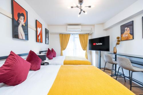 two beds with red pillows in a hotel room at Nakatsu Sakae Manshon in Osaka