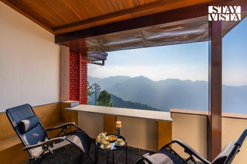 a room with chairs and a table with a view of mountains at StayVista at Cheerio - Elysium Estate 2BR Cottage with Valley View in Shimla