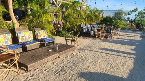 a wooden bench on the beach with chairs and tables at Fumba Town Tausi Apartments in Zanzibar City