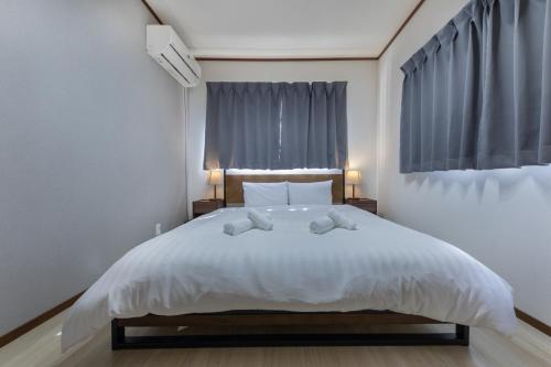 a bedroom with a large white bed with two pillows at Kaori 香 in Osaka