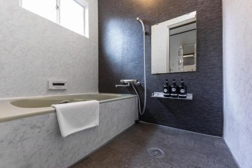 a bathroom with a bath tub and a sink at Kaori 香 in Osaka