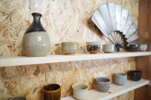 a shelf with cups and a vase and a fan at 一棟貸切AKARIYA Home in Karatsu