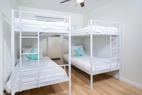 two white bunk beds in a room with wood floors at Newly Built Coastal Home with Yard in San Diego