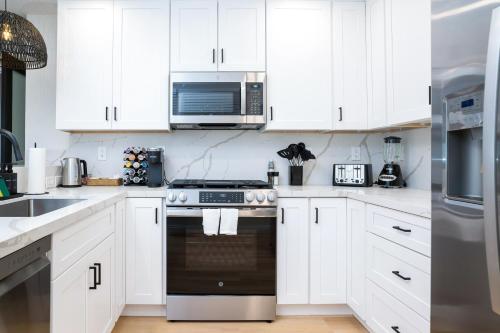 a kitchen with white cabinets and a stove top oven at Newly Built Coastal Home with Yard in San Diego