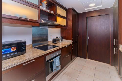 a kitchen with wooden cabinets and a microwave at Savis Homes - Luxury 2 Bedroom Suite with Full Burj Khalifa View in Dubai