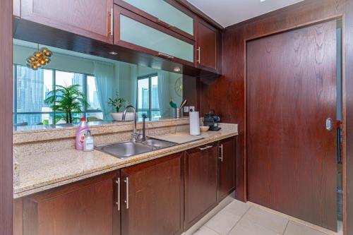 a kitchen with wooden cabinets and a sink and a mirror at Savis Homes - Luxury 2 Bedroom Suite with Full Burj Khalifa View in Dubai