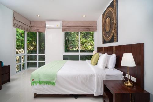 a bedroom with a large white bed and windows at Surin Park by Destada in Surin Beach