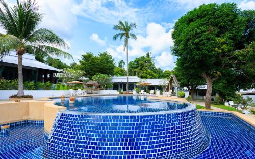 a swimming pool with a blue tile floor and trees at Peace Garden Resort, Koh Samui in Bangrak Beach