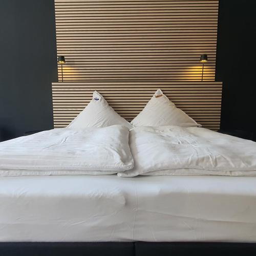 a bed with white sheets and pillows on it at SAM - your cozy stay near Hamburg-Airport in Hamburg