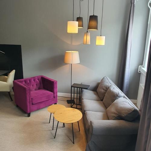 a living room with a couch and a pink chair at SAM - your cozy stay near Hamburg-Airport in Hamburg
