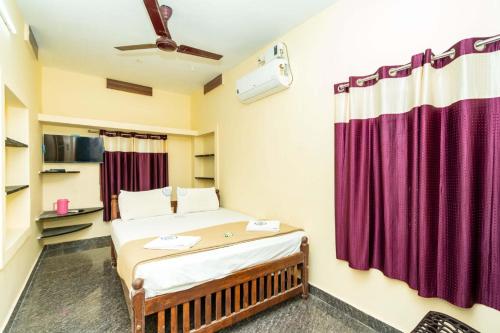 a bedroom with a bed with purple curtains at Amman Villa - Home Stay in Rāmeswaram