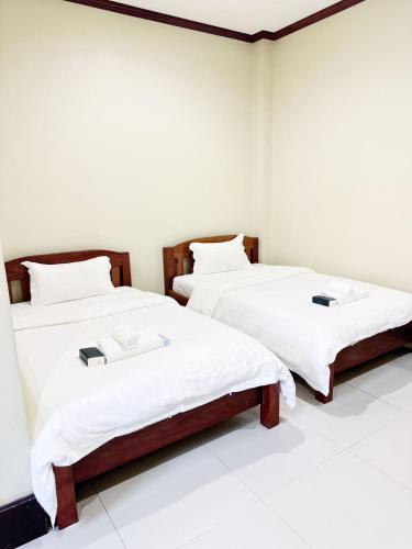 two beds in a room with white sheets at Happy Hotel in Vang Vieng