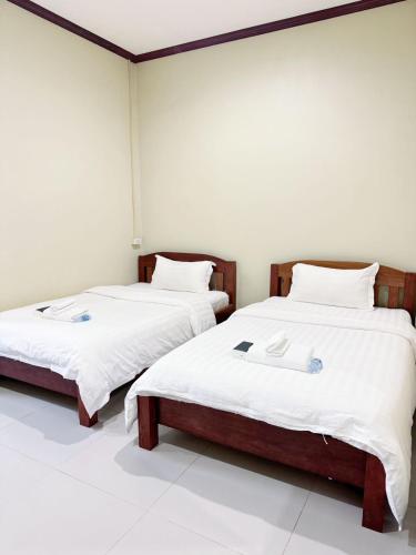 two beds in a room with white walls at Happy Hotel in Vang Vieng