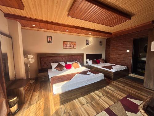 a bedroom with two beds and a wooden ceiling at Traditional Hotel & Restaurant !! Kurseong !! Best Hotel in Kurseong in Darjeeling