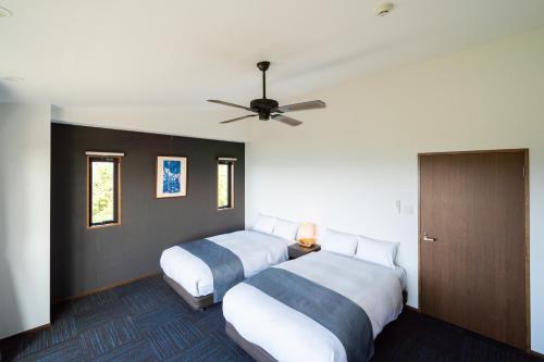 a bedroom with two beds and a ceiling fan at ホテルコンドミニアム土花土花 in Onna