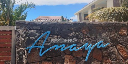 a sign on a stone wall in front of a house at Anaya Résidence in Flic-en-Flac