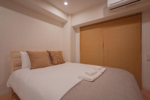 a bedroom with a bed with two towels on it at Tenkawa Inn Umedahigashi in Osaka