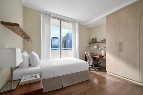 a bedroom with a bed and a desk and a window at Somerset Chancellor Court Ho Chi Minh City in Ho Chi Minh City