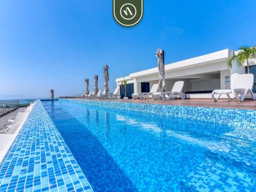 a swimming pool with chaise lounge chairs next to a building at Luxury Oceanfront 3 BR Condo - Private Jacuzzi in Cruz de Huanacaxtle