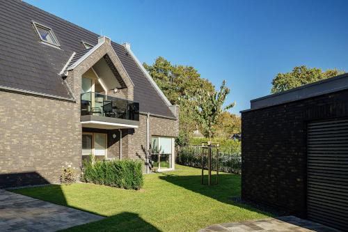 a brick house with a balcony and a yard at Ferienwohnung Hafenkieker in Born